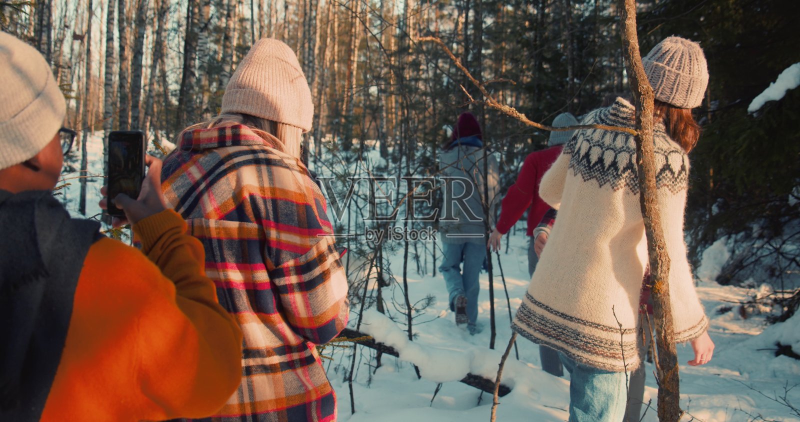 后视组的多民族快乐的朋友走在阳光明媚的雪冬森林小路享受周末的慢动作。照片摄影图片