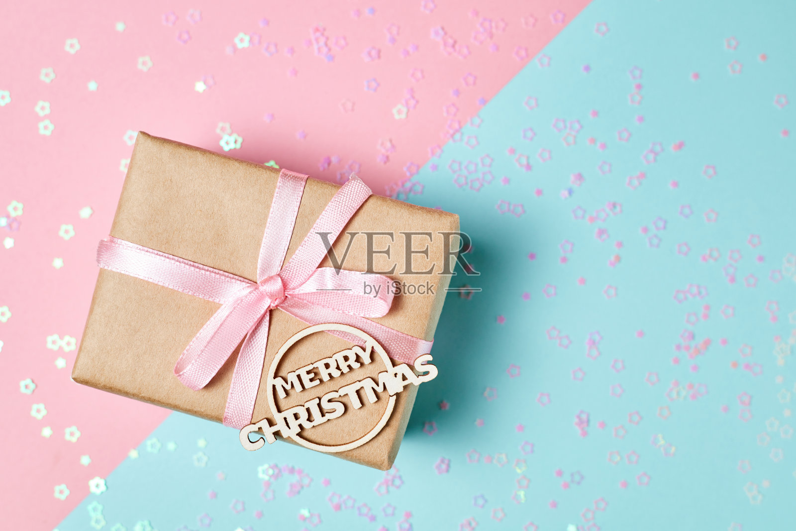 圣诞礼盒以粉红色缎带和题词圣诞快乐在粉红色和蓝色的背景与圣诞火花照片摄影图片
