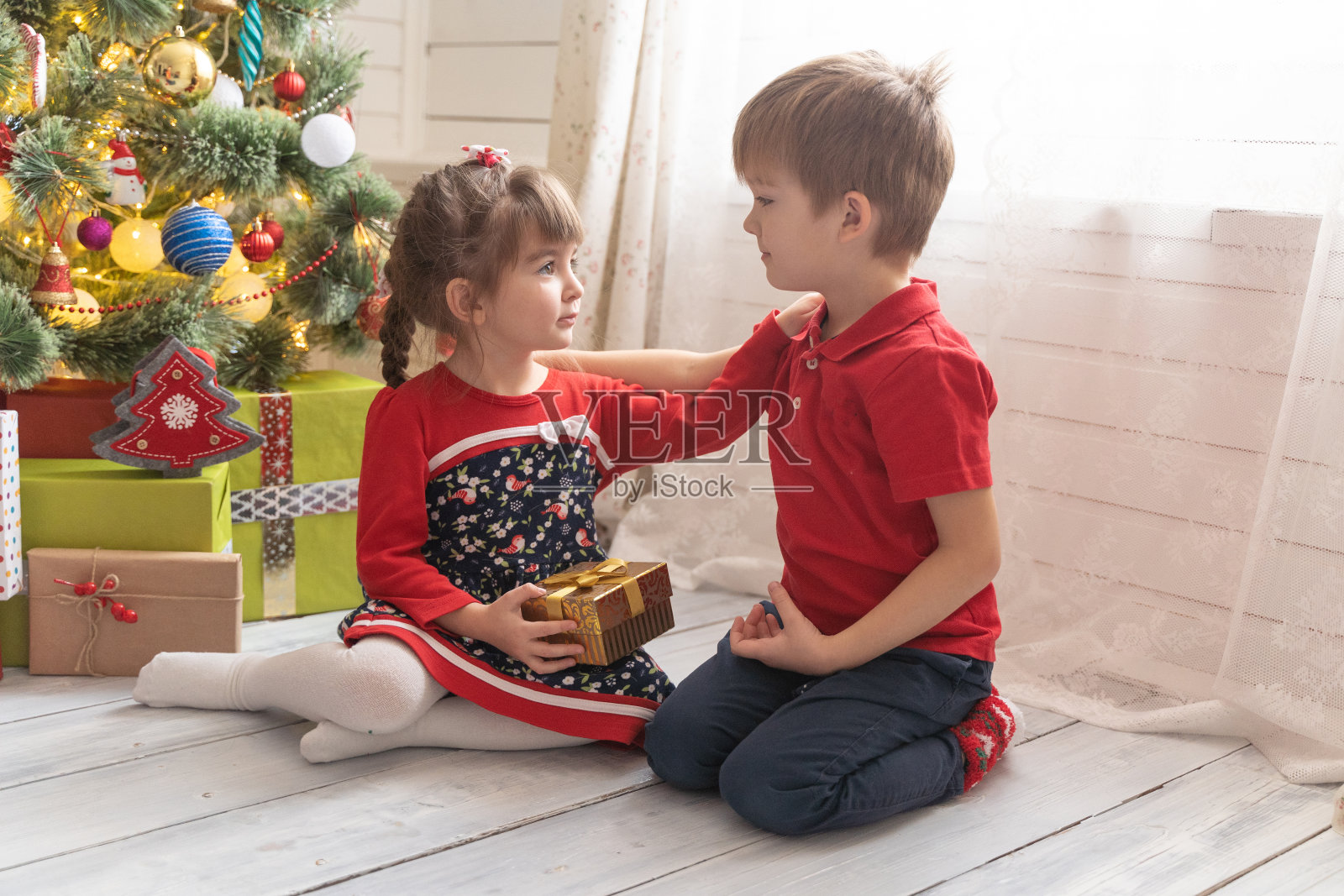 在一间阳光明媚的房间里，男孩给了女孩一份圣诞礼物照片摄影图片