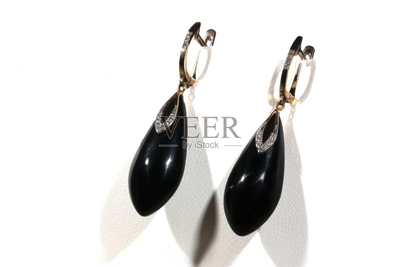 白色底色上镶有缟玛瑙和钻石的金耳环。长耳环。女性的配件照片摄影图片