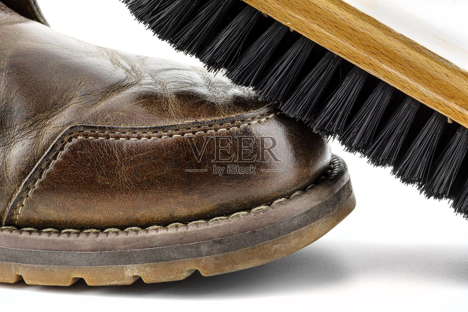 微距照片的旧棕色皮靴抛光膏，鞋刷躺在鞋子上，孤立在白色的背景。照片摄影图片