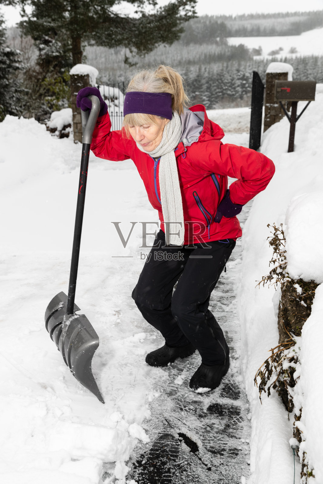 因使用雪铲而背部疼痛的妇女照片摄影图片