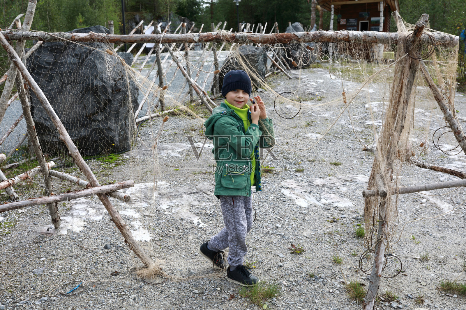 孩子旁边的旧渔网挂在木架上照片摄影图片