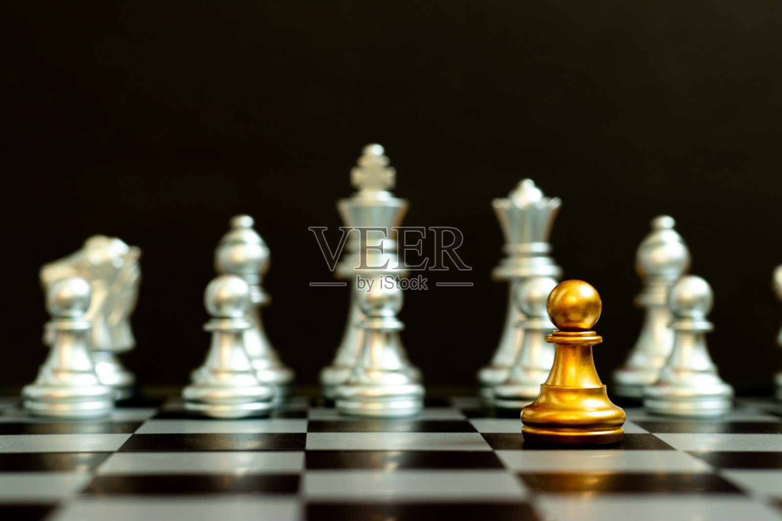 棋局中的金卒在黑色背景下面对另一支银队(用于公司战略、业务胜利或决策的概念)照片摄影图片