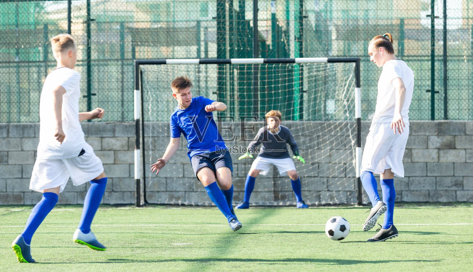 两队穿着白色和蓝色衬衫的青少年之间的足球比赛照片摄影图片