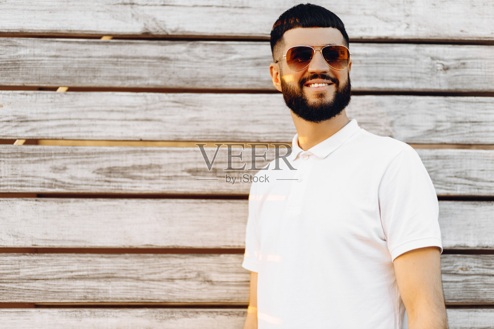 有胡子的时髦男人，站在木制背景上，有你的短信或广告的复制空间照片摄影图片