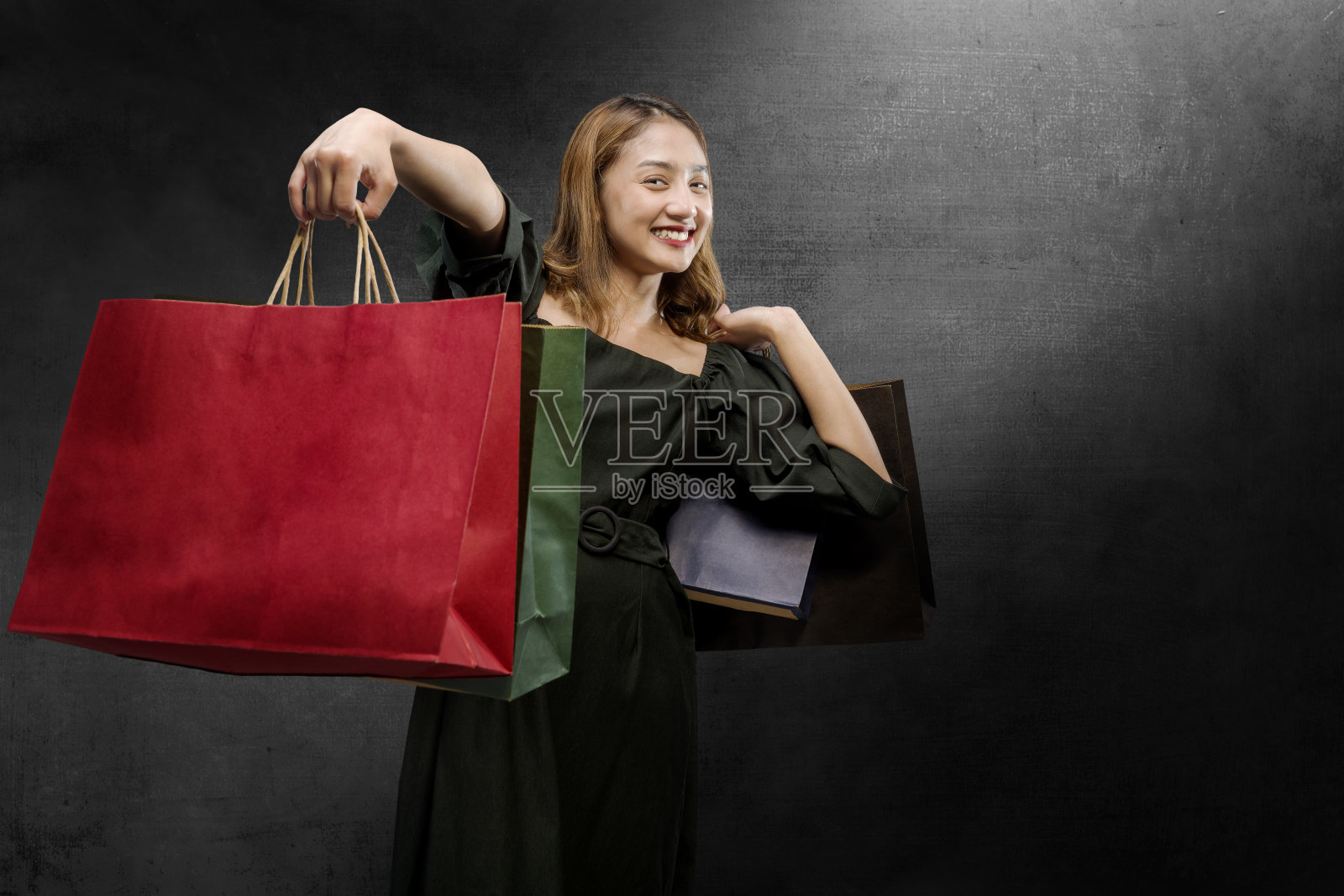 一位亚洲妇女背着一个黑色背景的购物袋照片摄影图片