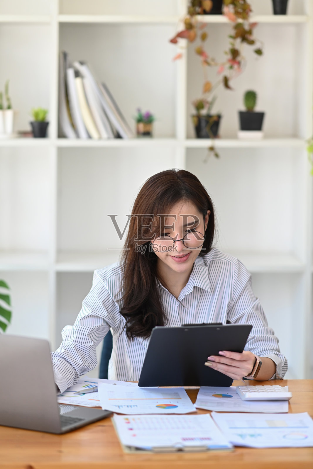 女会计师用笔记本电脑工作，检查财务报告。照片摄影图片