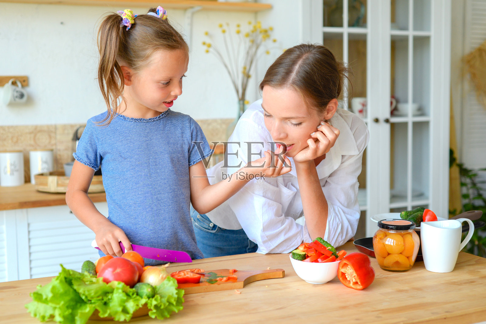 妈妈和小女儿正在厨房里准备健康的食物。素食主义。饮食。健康的生活方式照片摄影图片