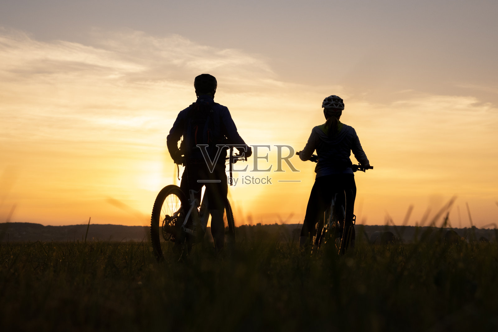 球场上骑着自行车的情侣剪影照片摄影图片