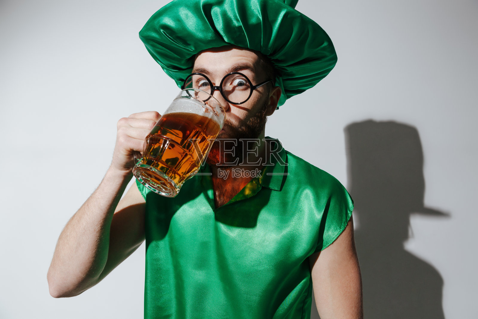 穿着圣派特里克斯服装的惊讶男子喝着啤酒照片摄影图片