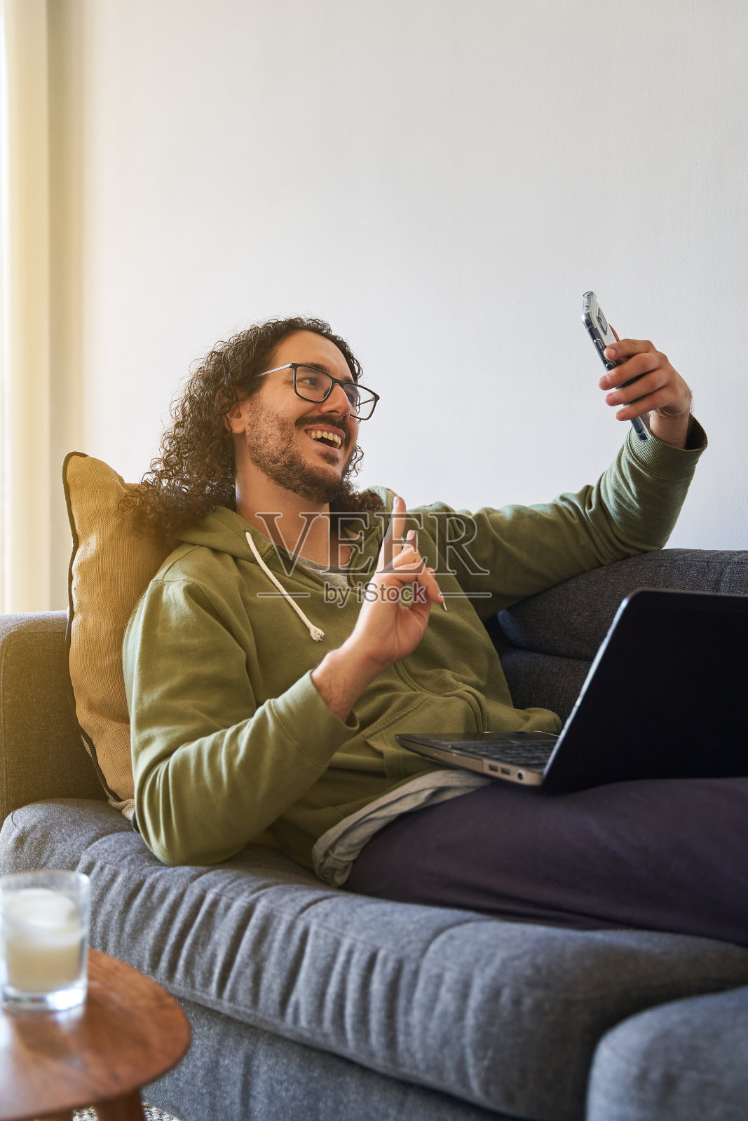 年轻男人在沙发上使用笔记本电脑自拍的竖版中景拍摄照片摄影图片