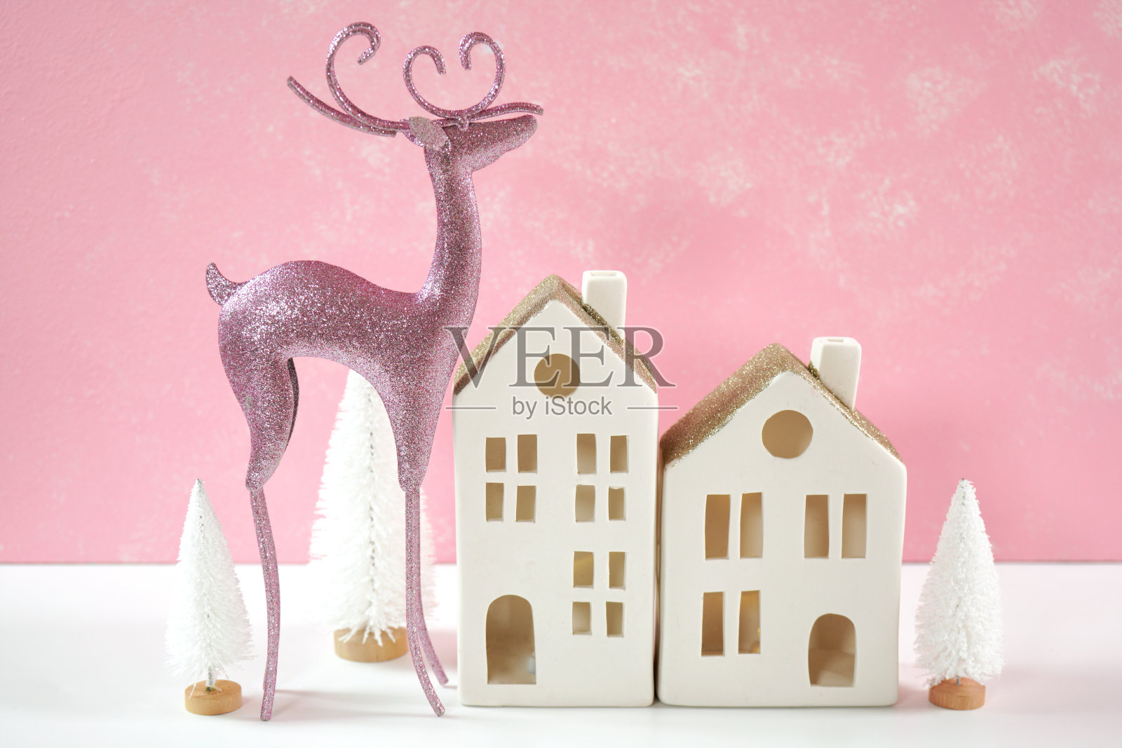 粉色圣诞驯鹿和村庄房屋装饰静物。照片摄影图片