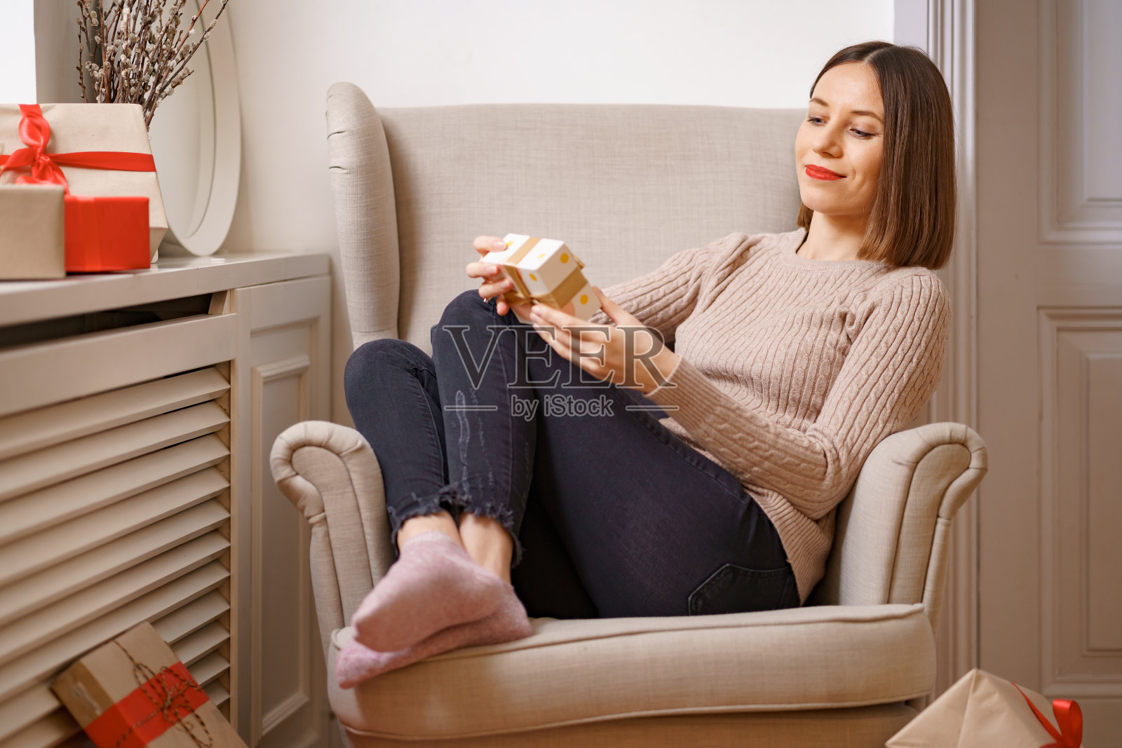 一位妇女坐在家里的扶手椅上，手里拿着一件礼物照片摄影图片