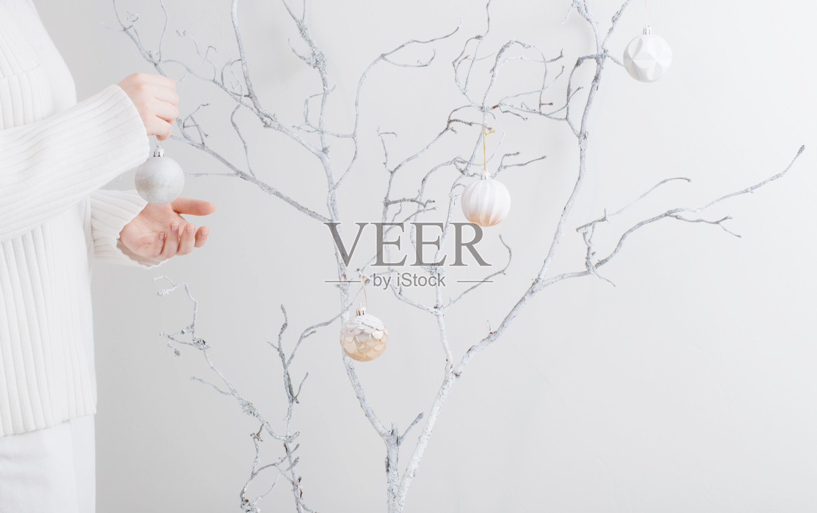 年轻女子拿着圣诞球和白色树枝在室内照片摄影图片