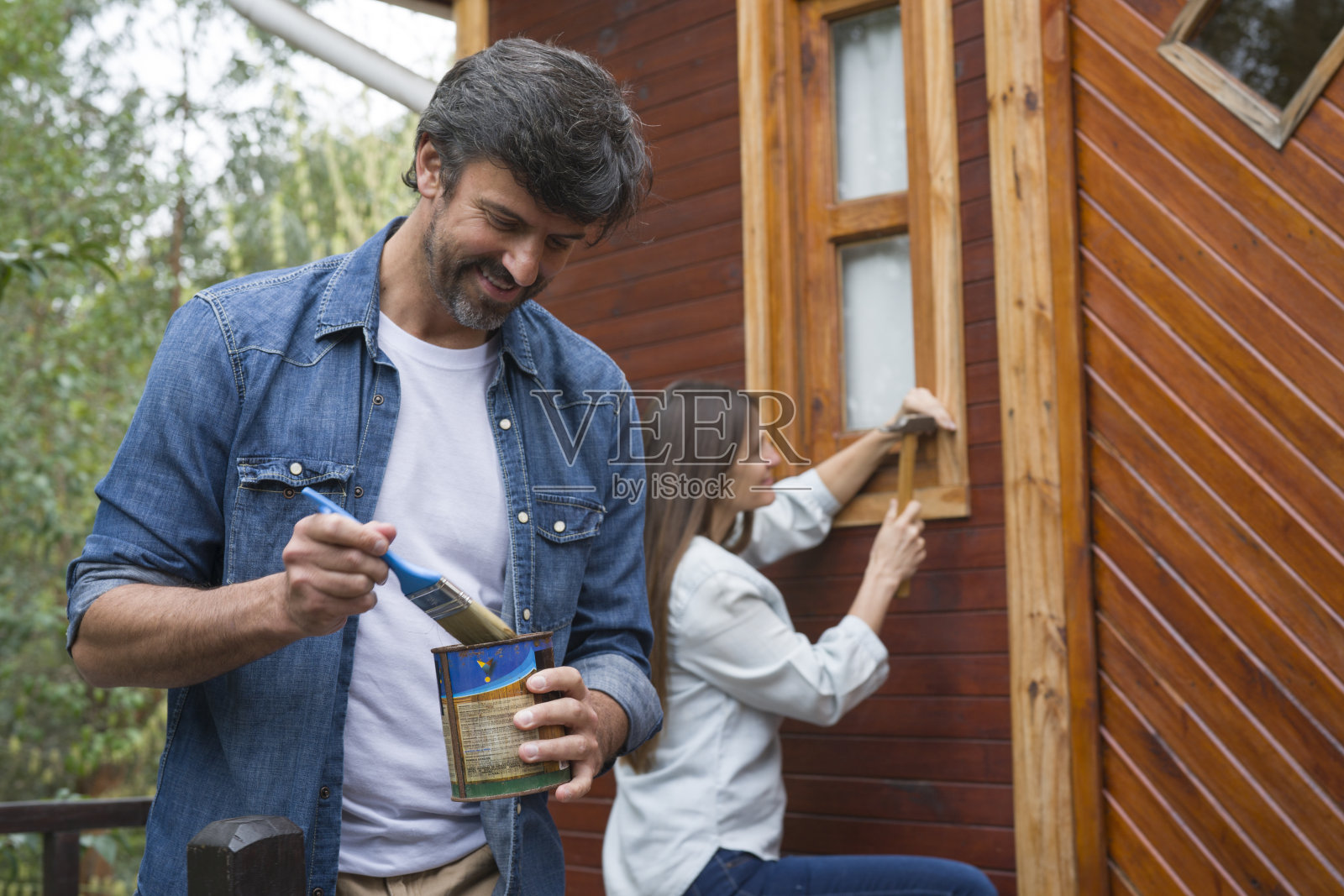 一对快乐的夫妇正在修理荒野度假村的小屋照片摄影图片