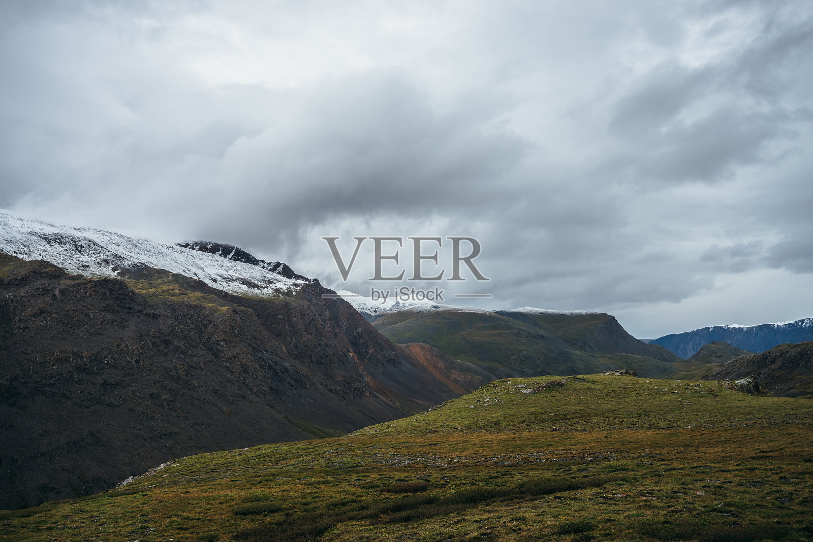 大气高山景观，深谷深谷，阴天积雪覆盖的多色山脉。在多云的天空下，白雪覆盖的山脉是美丽的风景。白雪覆盖的高山照片摄影图片