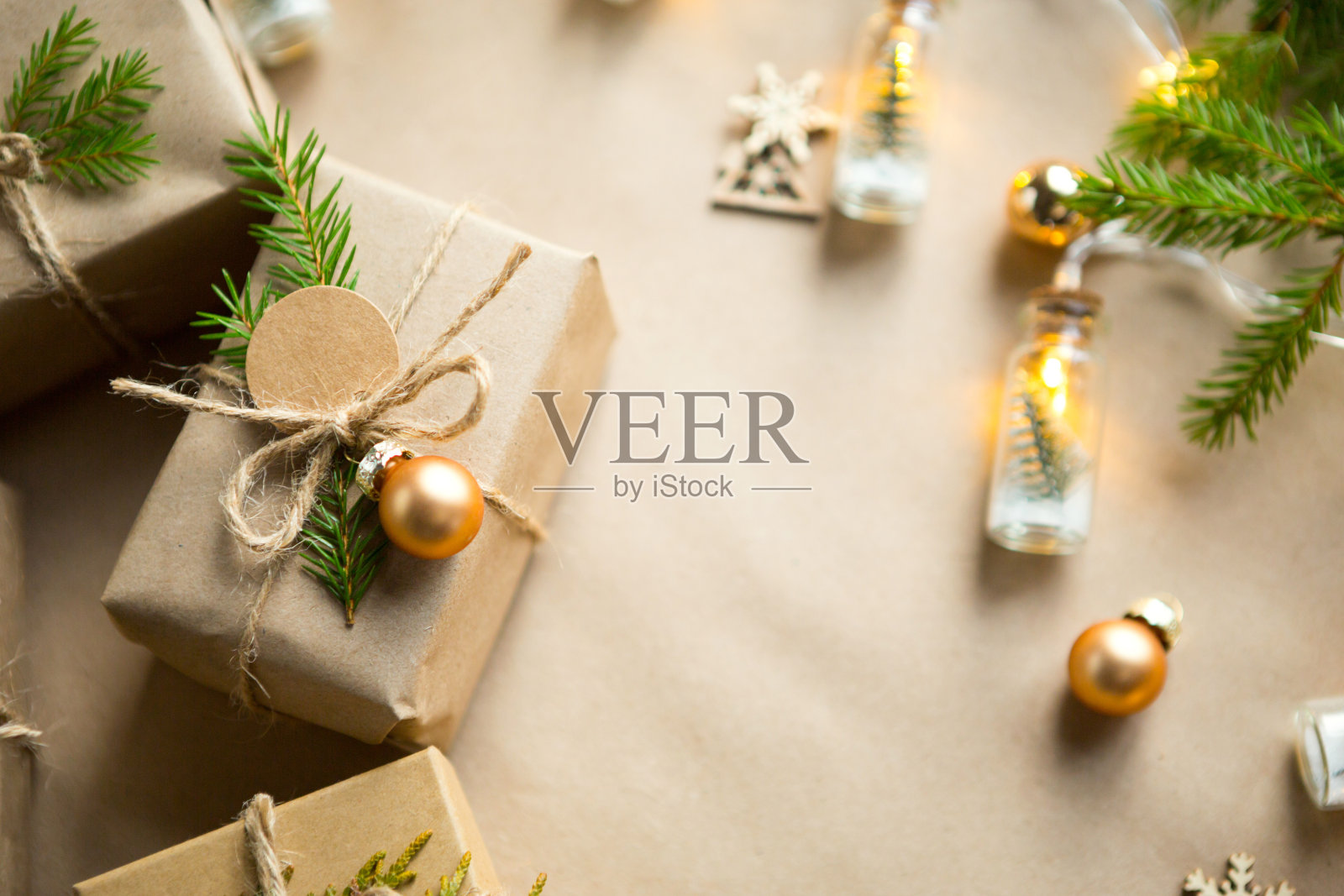 用环保材料打包圣诞和新年的礼物:牛皮纸、活杉木树枝、松果和麻绳。标签与模拟，自然装饰，手工制作，DIY。节日的气氛中。圣诞节的背景照片摄影图片