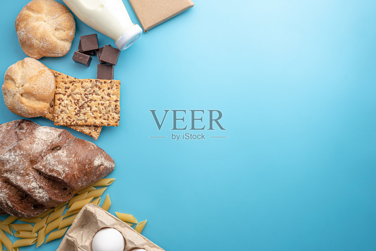 新鲜食物在蓝色背景俯视图。面包、巧克力、牛奶、鸡蛋等产品送货上门。本空间照片摄影图片