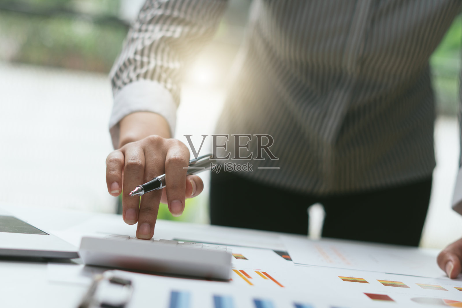 近手商人或会计手拿着笔在计算器上计算业务数据，会计文件和笔记本电脑在办公室，业务概念。照片摄影图片