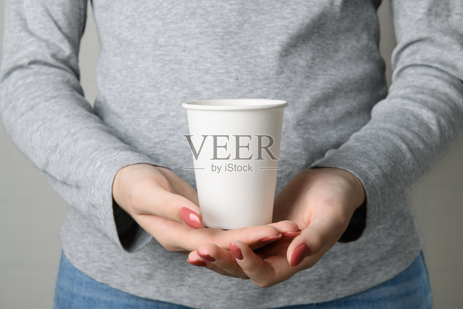 没有脸的女人拿着空白的空从底部拿走纸杯照片摄影图片