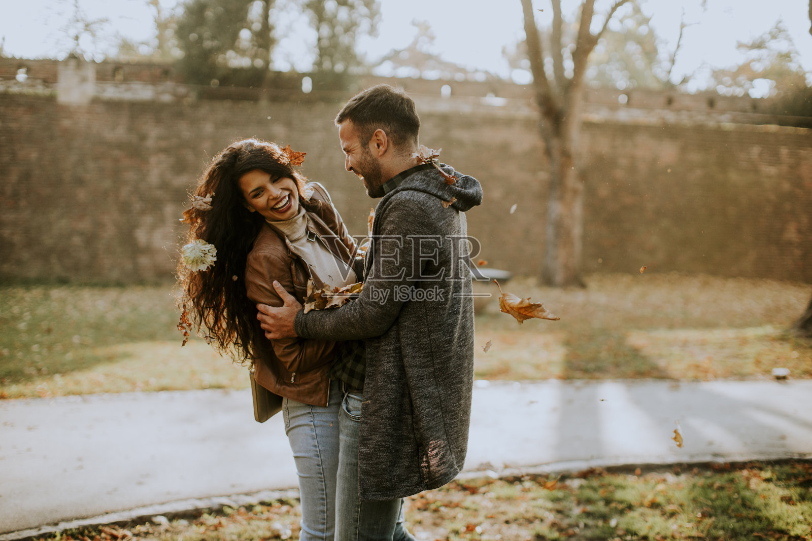 年轻夫妇在公园里与秋叶玩耍照片摄影图片