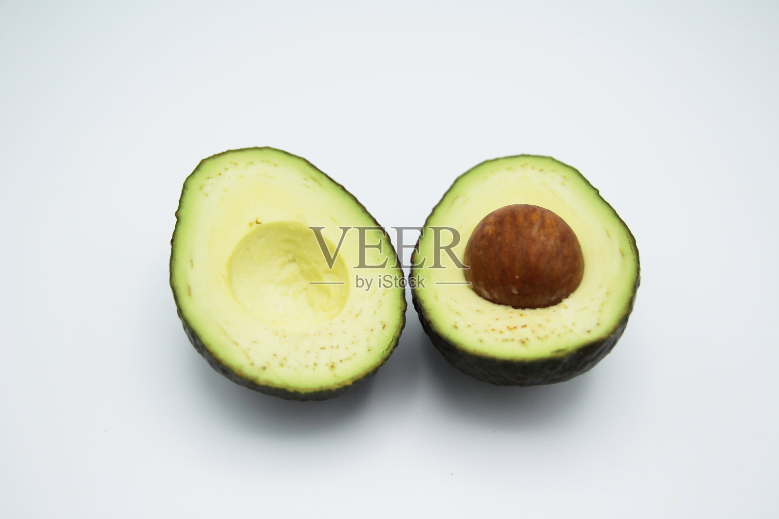 牛油果切成两半放在白色背景上照片摄影图片