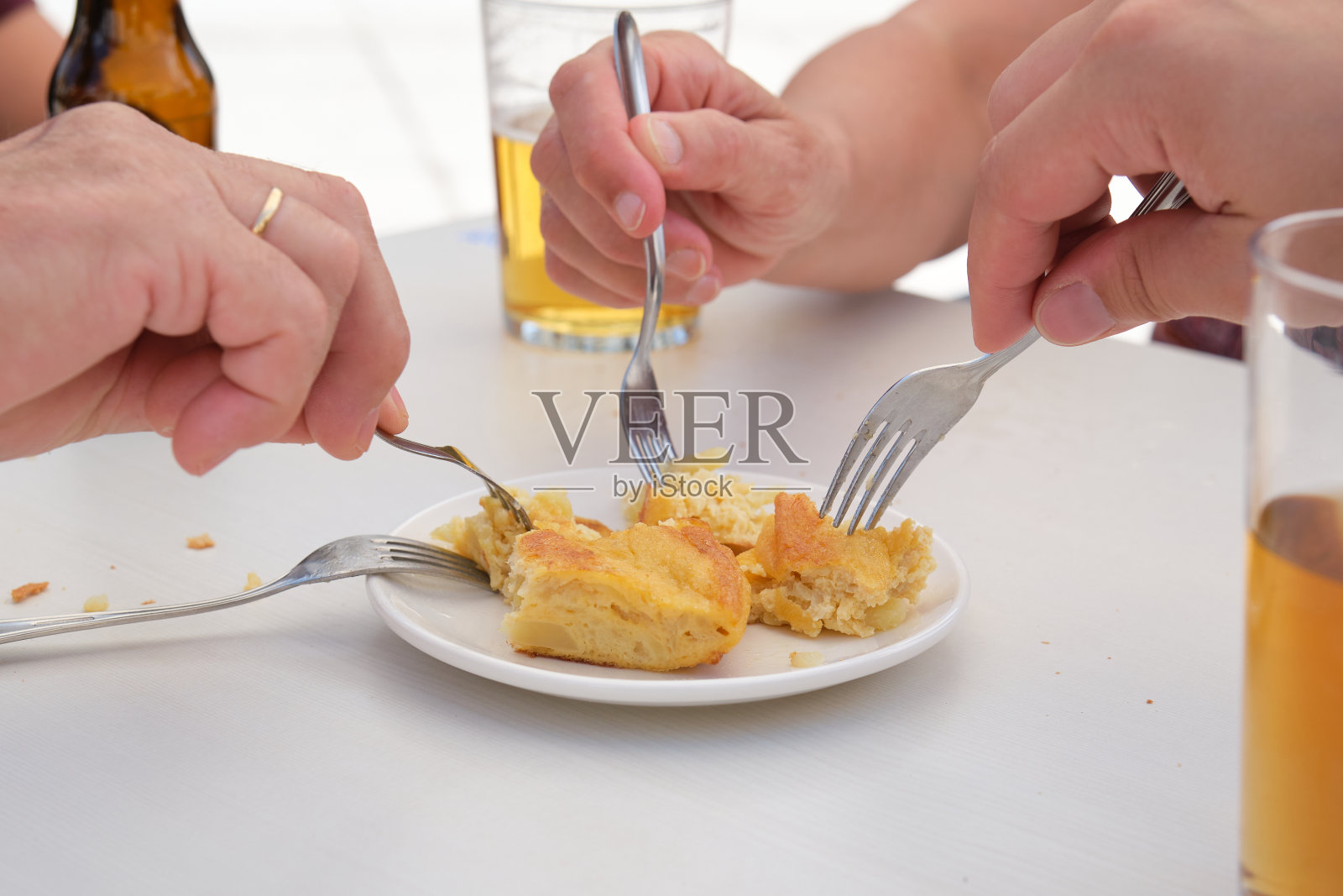 一群人吃着西班牙煎蛋卷，喝着啤酒。照片摄影图片