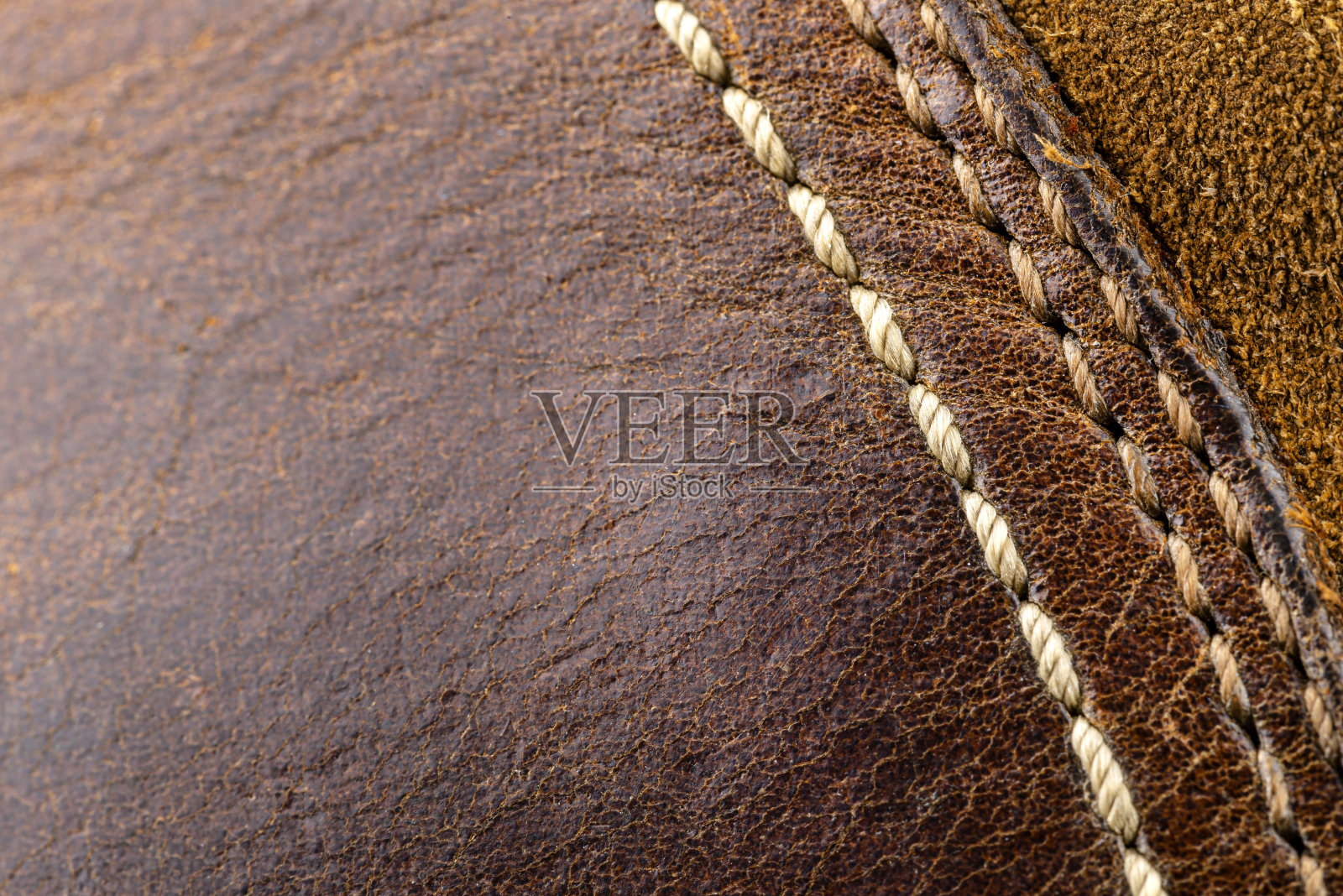 宏观背景制成的棕色天然皮革与白色缝合在右侧。照片摄影图片