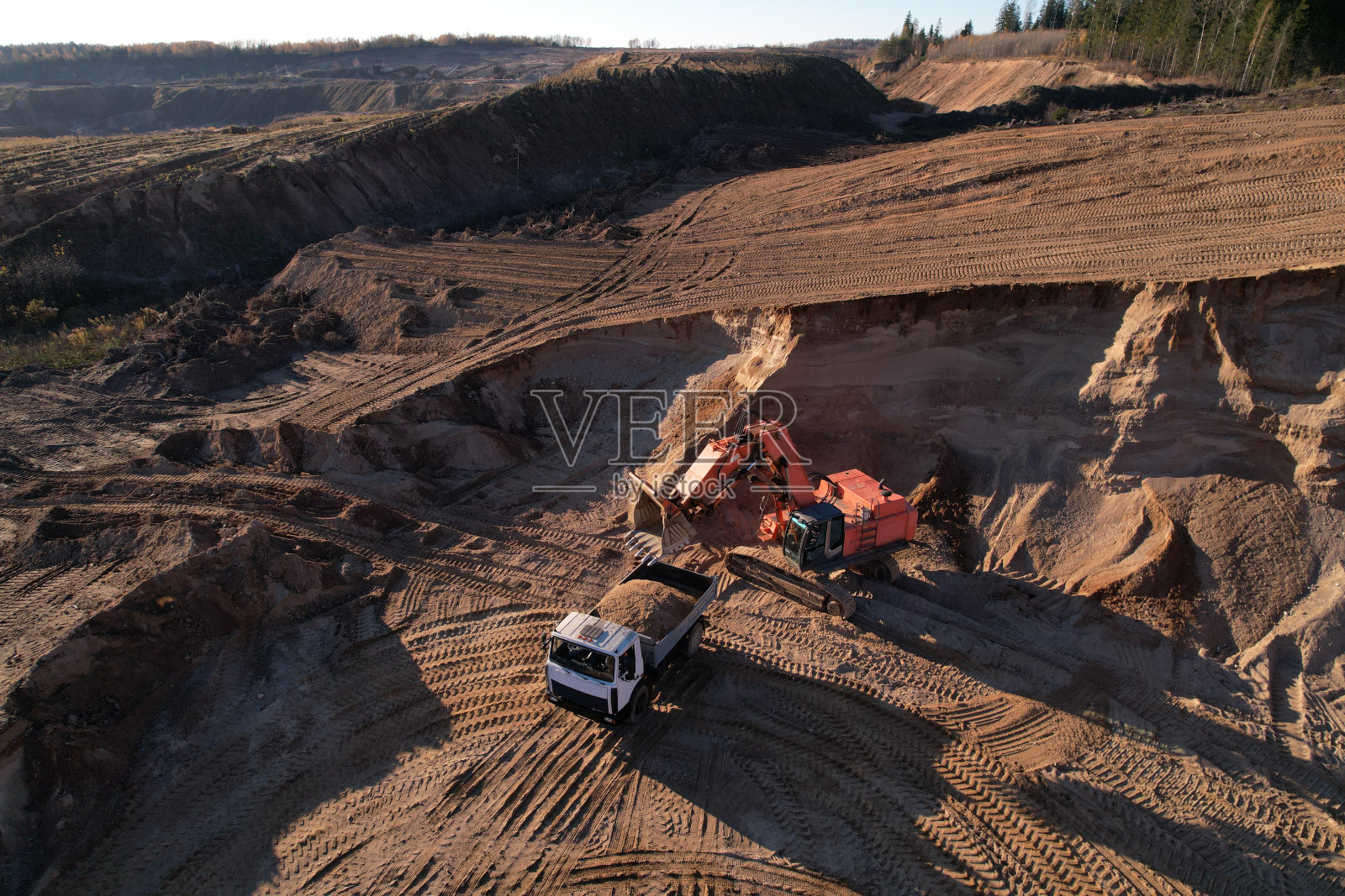 露天矿场挖掘机将沙子装入自卸卡车照片摄影图片