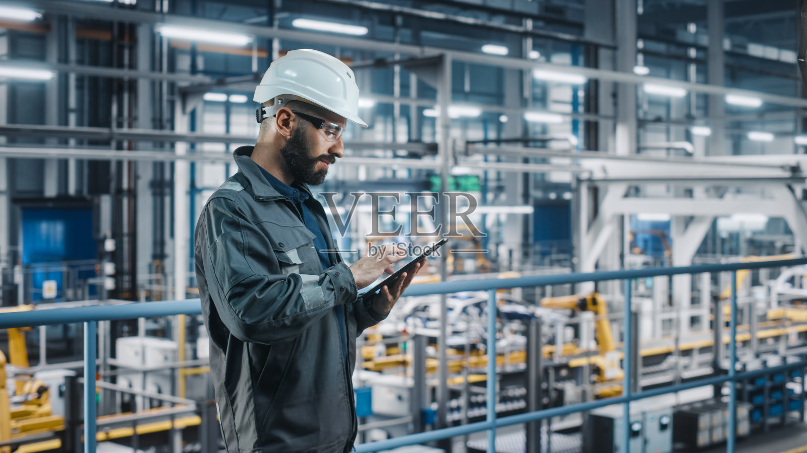 汽车工厂工程师穿着工作服使用平板电脑。汽车工业4.0制造工厂使用机械臂技术生产汽车。自动组装厂。照片摄影图片