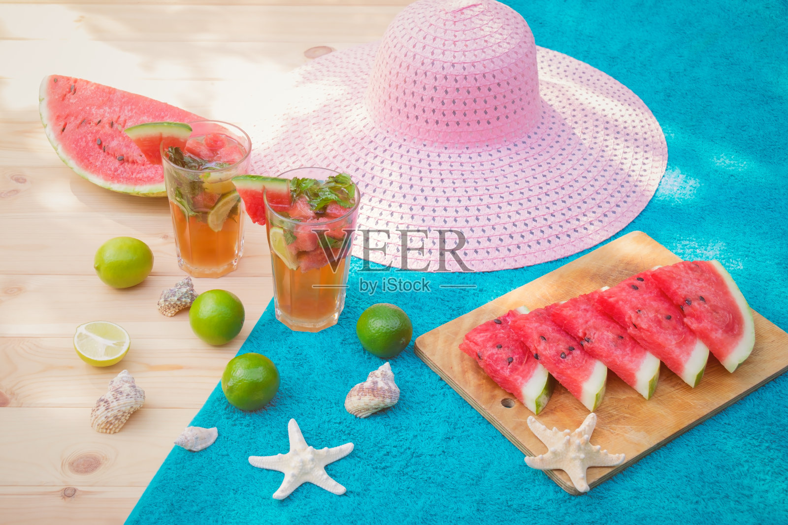 木桌上的西瓜莫吉托鸡尾酒。西瓜，酸橙，海星，贝壳和帽子。有选择性的重点。照片摄影图片