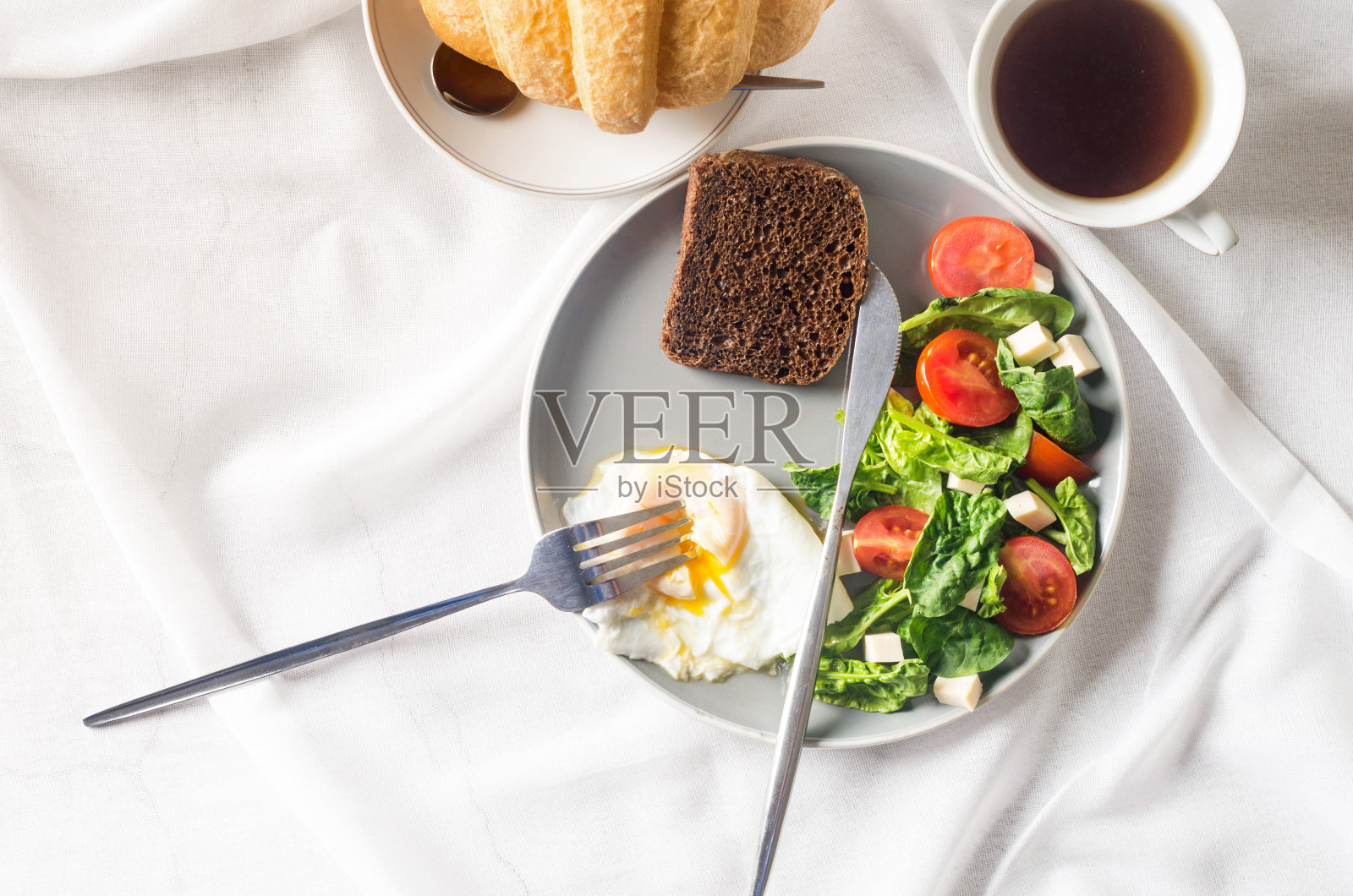 盘子里的沙拉，鸡蛋，一杯咖啡和羊角面包，花瓶里洁白的郁金香照片摄影图片