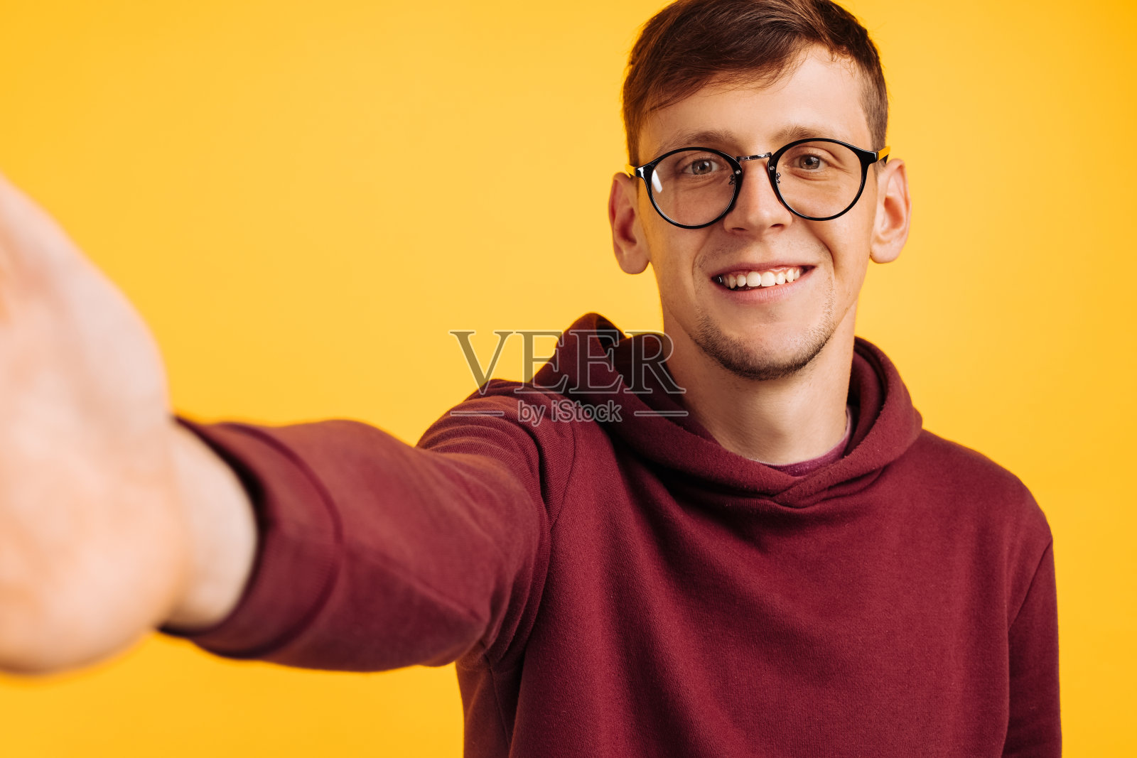 一个戴着眼镜微笑的男人自拍的特写。男子在孤立的黄色背景下自拍照片摄影图片