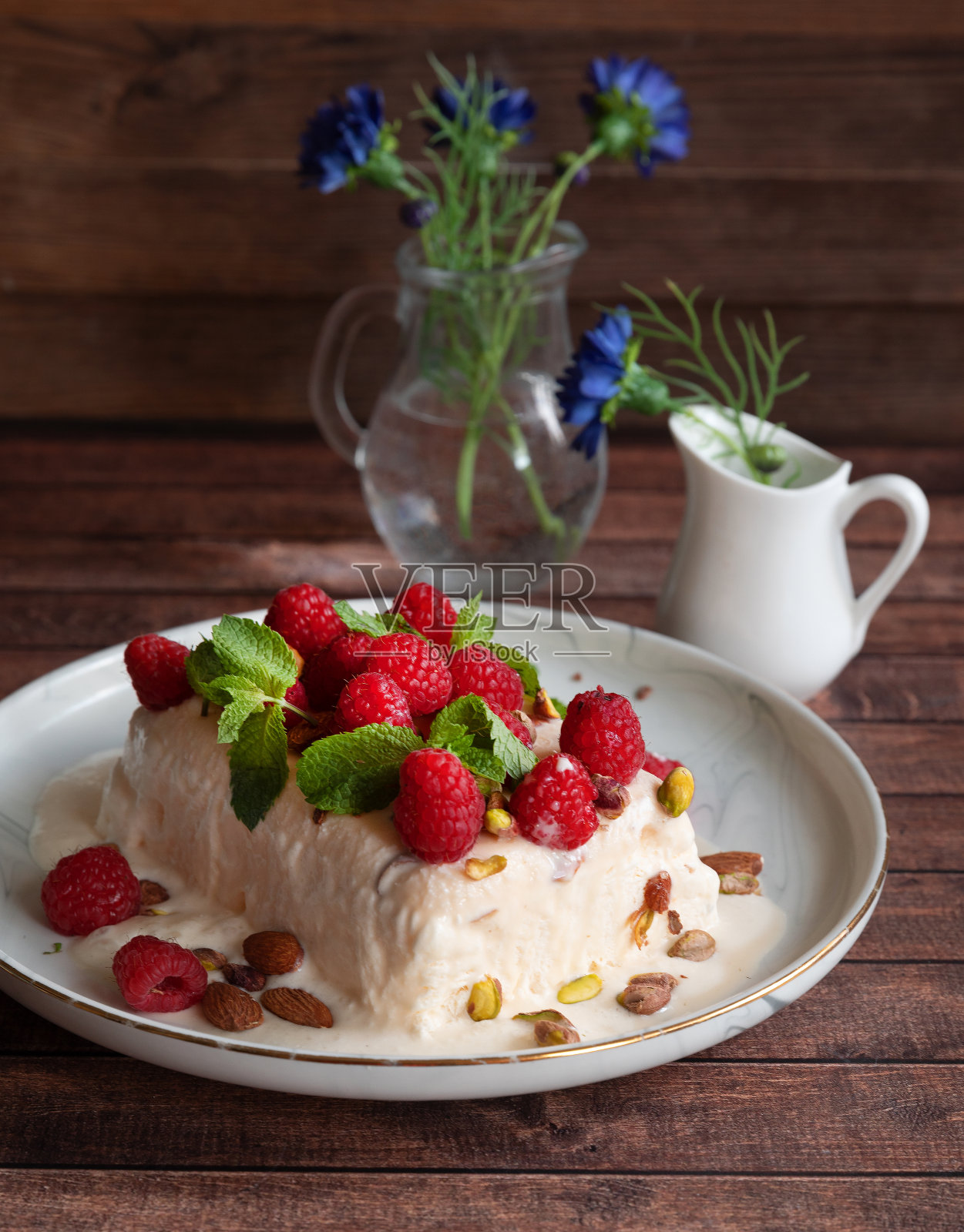 覆盆子冰淇淋甜点;木桌上用薄荷装饰的半花朵照片摄影图片