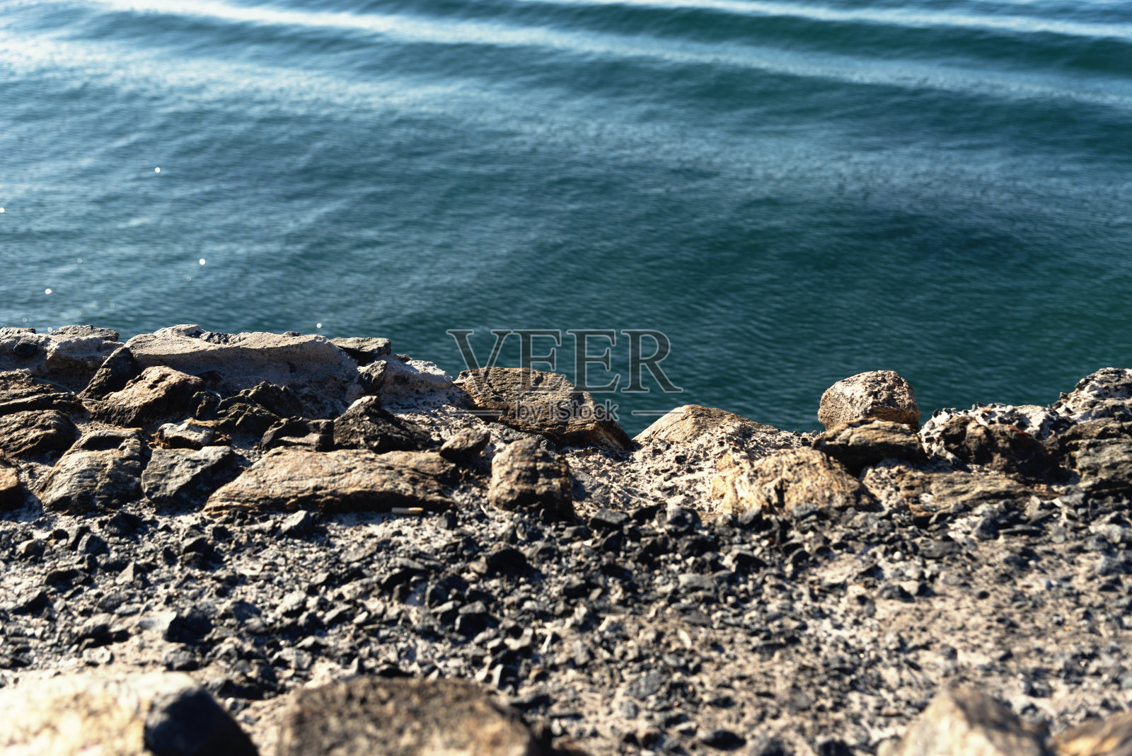 从石头人行道上看到的海边。照片摄影图片