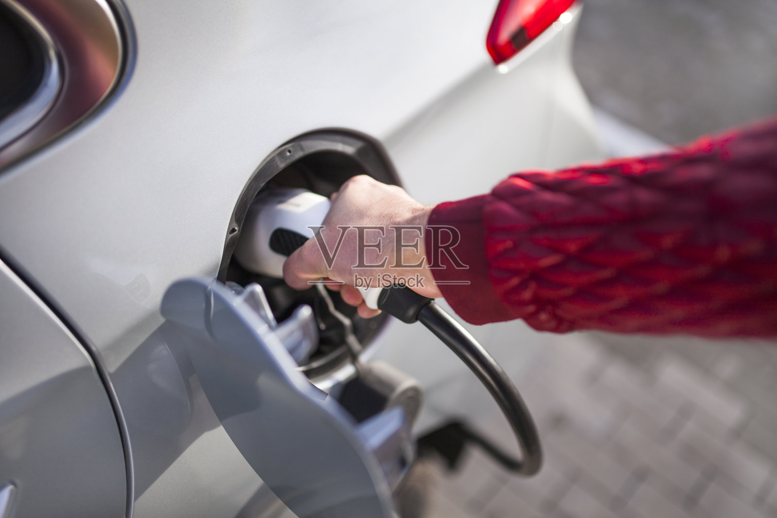 一个年轻人在停车场给他的电动汽车充电照片摄影图片