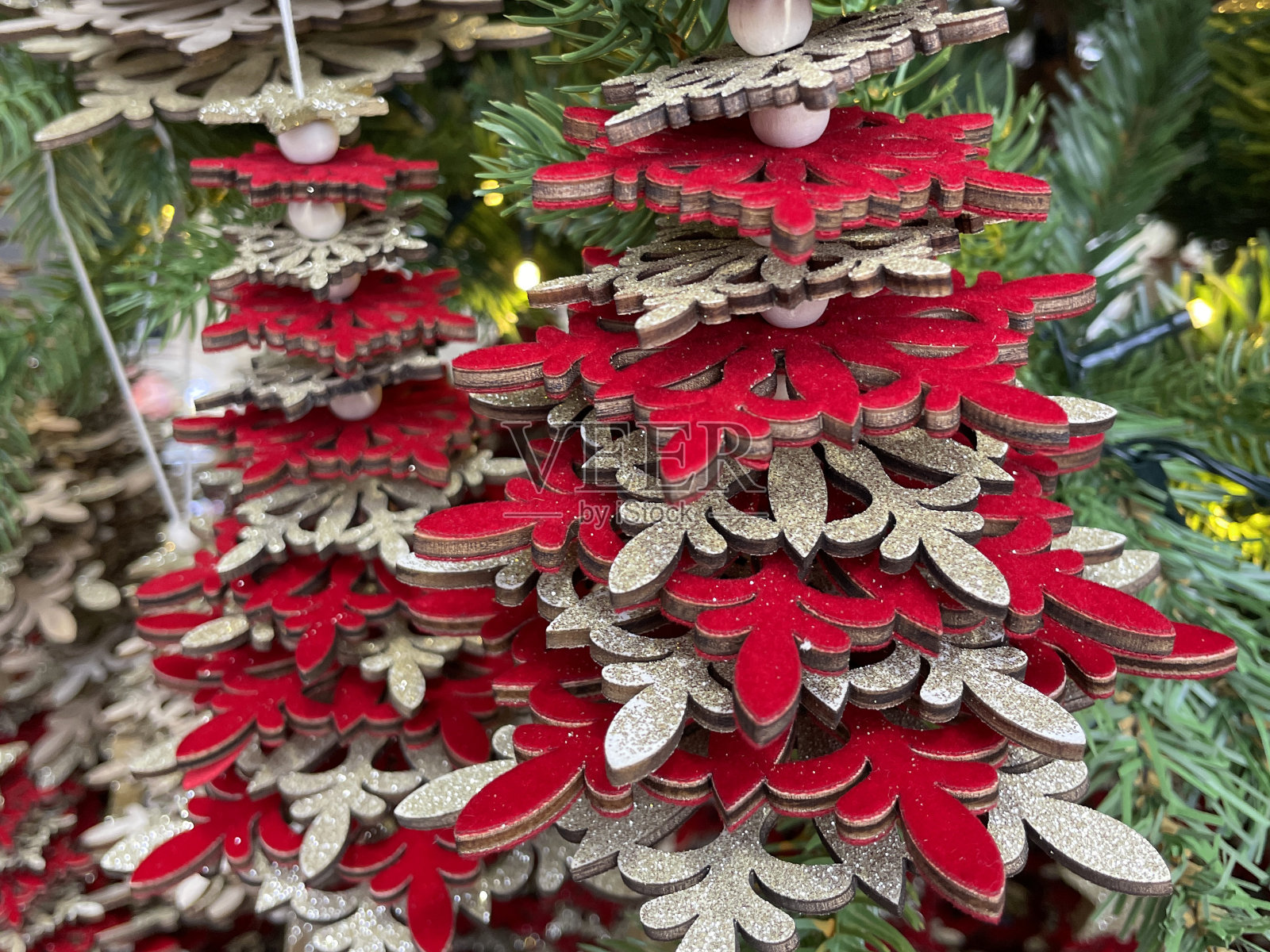 圣诞树装饰的特写图像由堆叠的红色和银色雪花形状的人造圣诞树树枝，绿色云杉针，模糊的白色精灵灯背景照片摄影图片