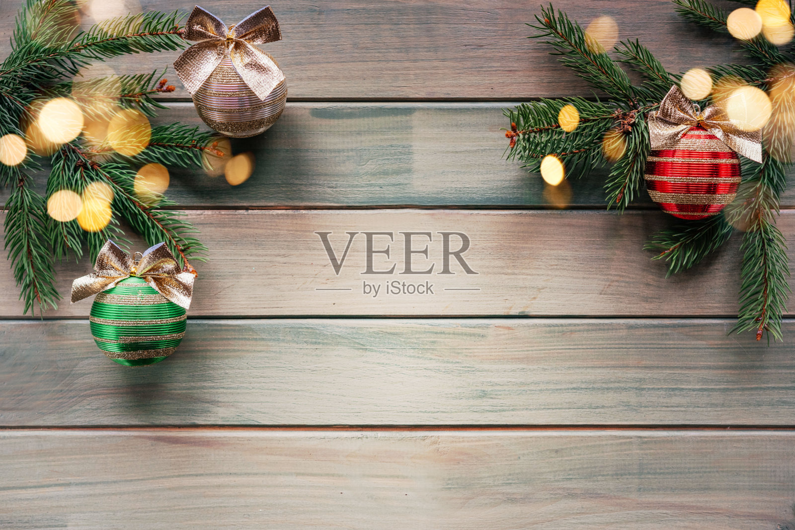 绿色，红色和银色的圣诞树球与金色的蝴蝶结，冷杉树枝和装饰品在木制背景与圣诞灯散景和复制空间照片摄影图片