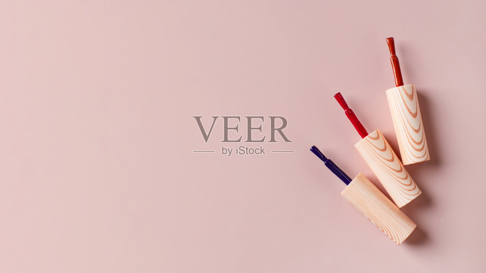 不同颜色的刷子明亮的指甲油瓶子浅粉色的背景。副本的空间。照片摄影图片