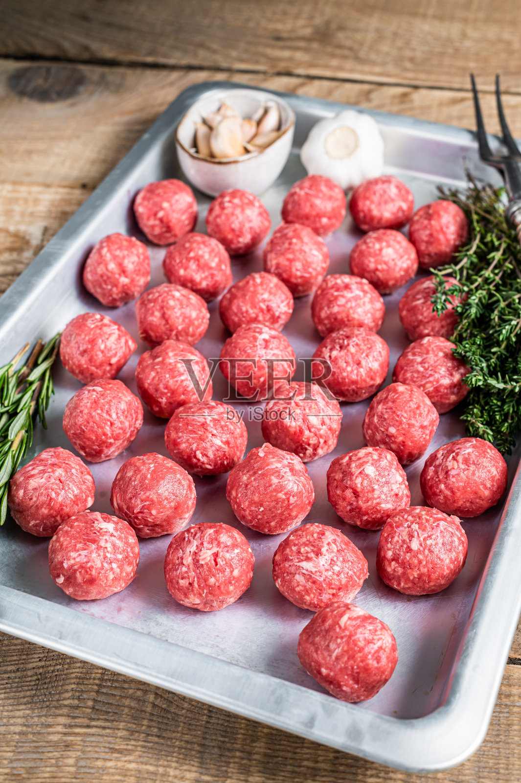 生牛肉和猪肉肉丸与百里香和迷迭香在厨房托盘。木制背景。俯视图照片摄影图片