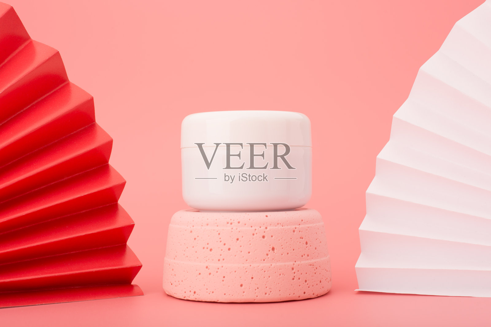 白色的化妆瓶放在粉红色的石膏基座上，粉红色的背景装饰着红白相间的波浪。豪华亚洲风格的护肤理念照片摄影图片