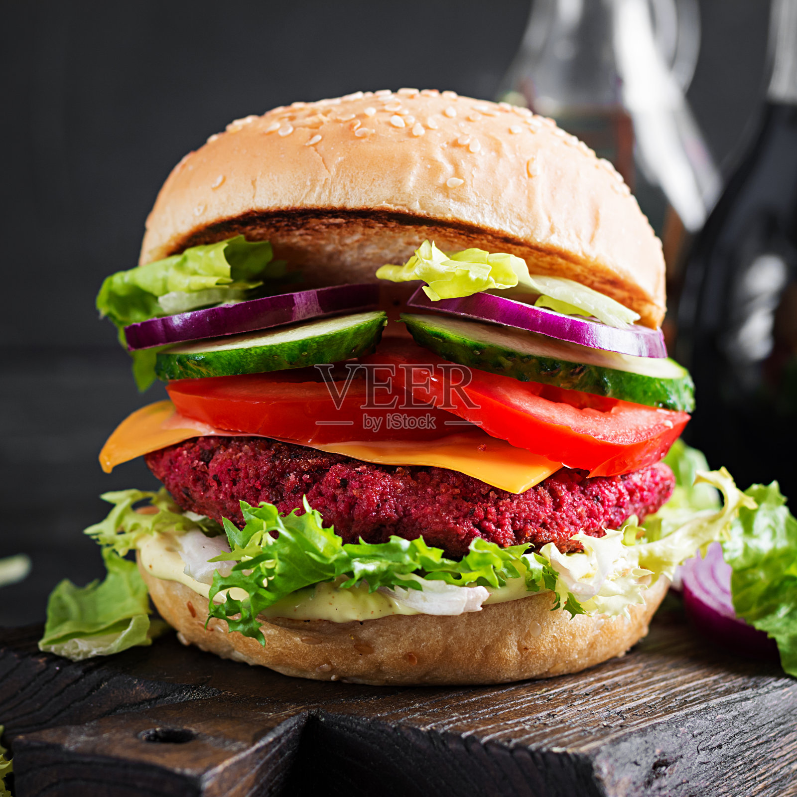 健康素食甜菜根汉堡配番茄、黄瓜、红洋葱和酱汁。黑暗的背景。副本的空间。照片摄影图片