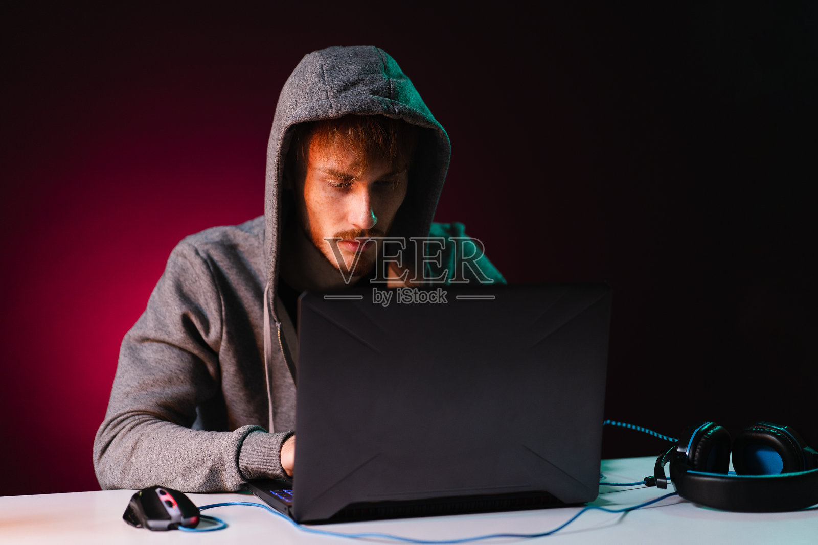 专业黑客与笔记本电脑坐在桌子在黑暗的背景照片摄影图片