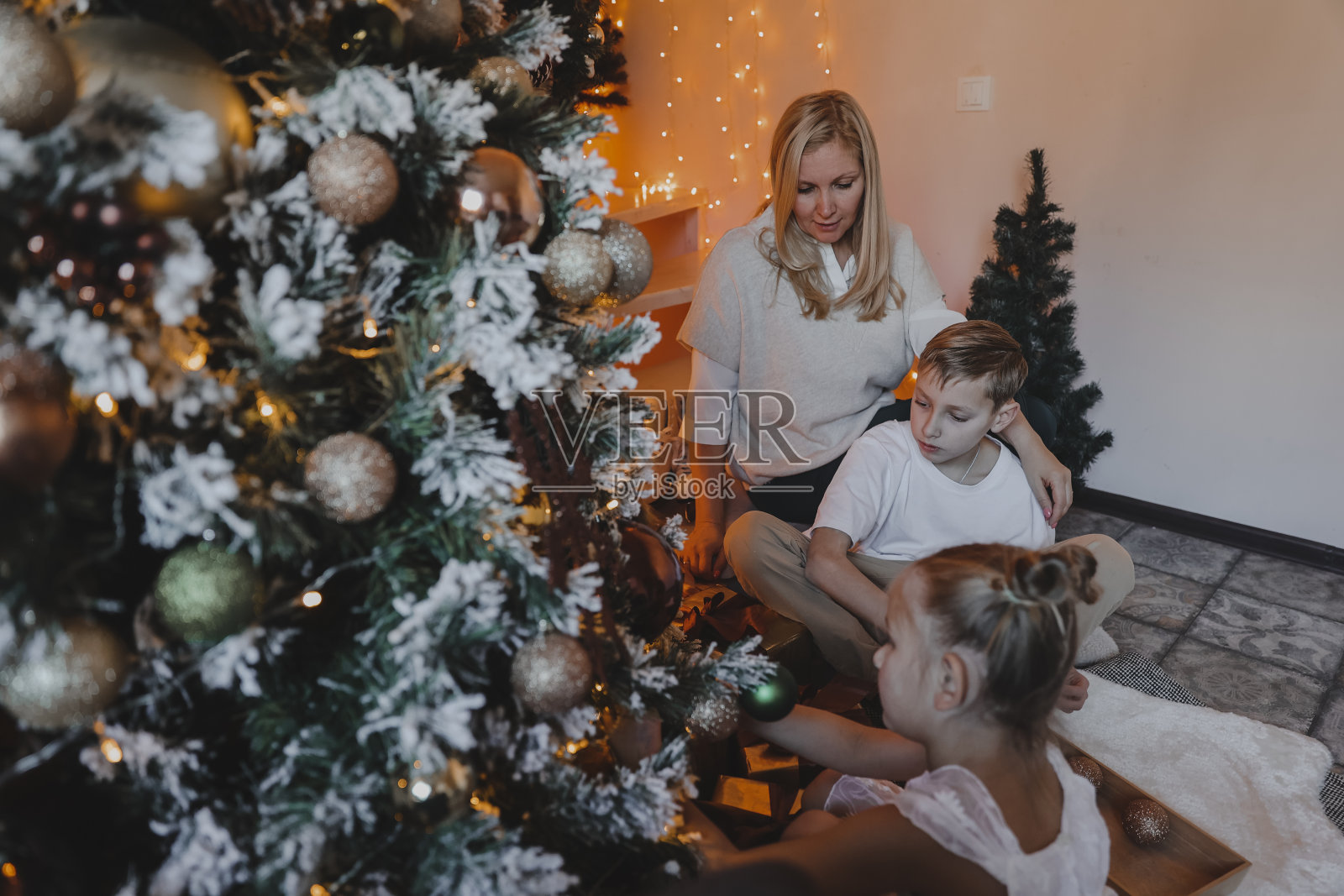 小朋友和妈妈装饰圣诞树，圣诞和新年快乐。家庭，冬季假期和人的概念，肖像爱的家庭近距离。照片摄影图片