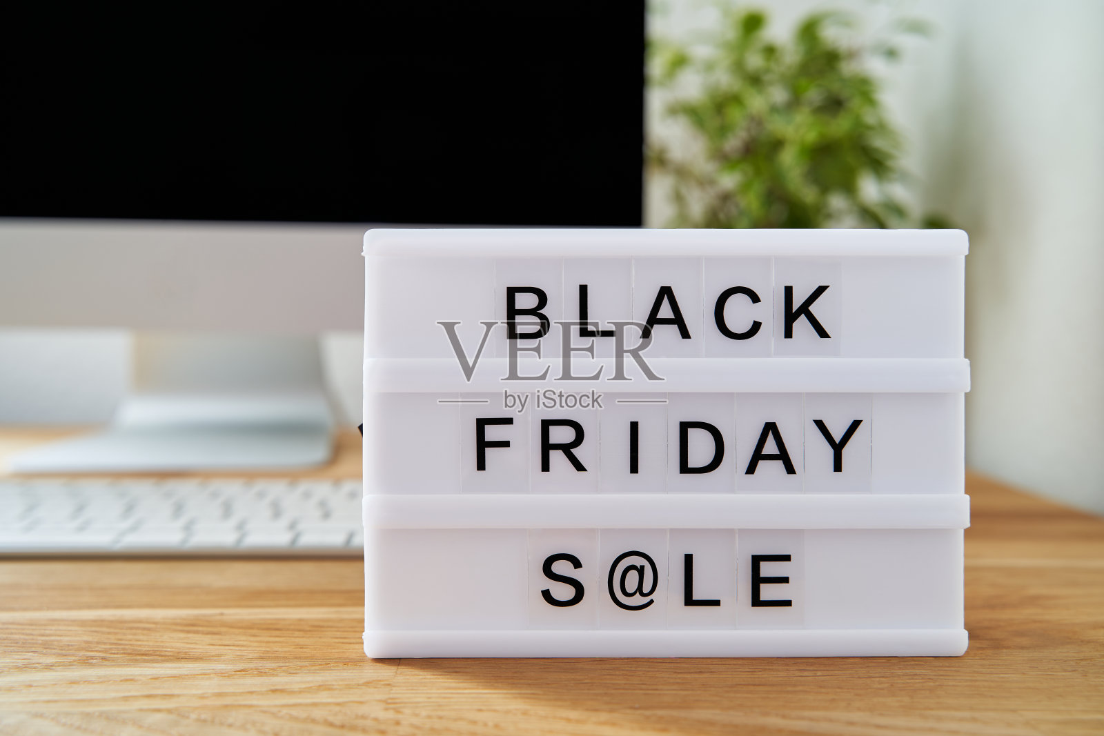 黑色星期五大甩卖写在灯箱上。灯箱在一张木制的桌子上。电脑背景模糊。黑色星期概念。照片摄影图片