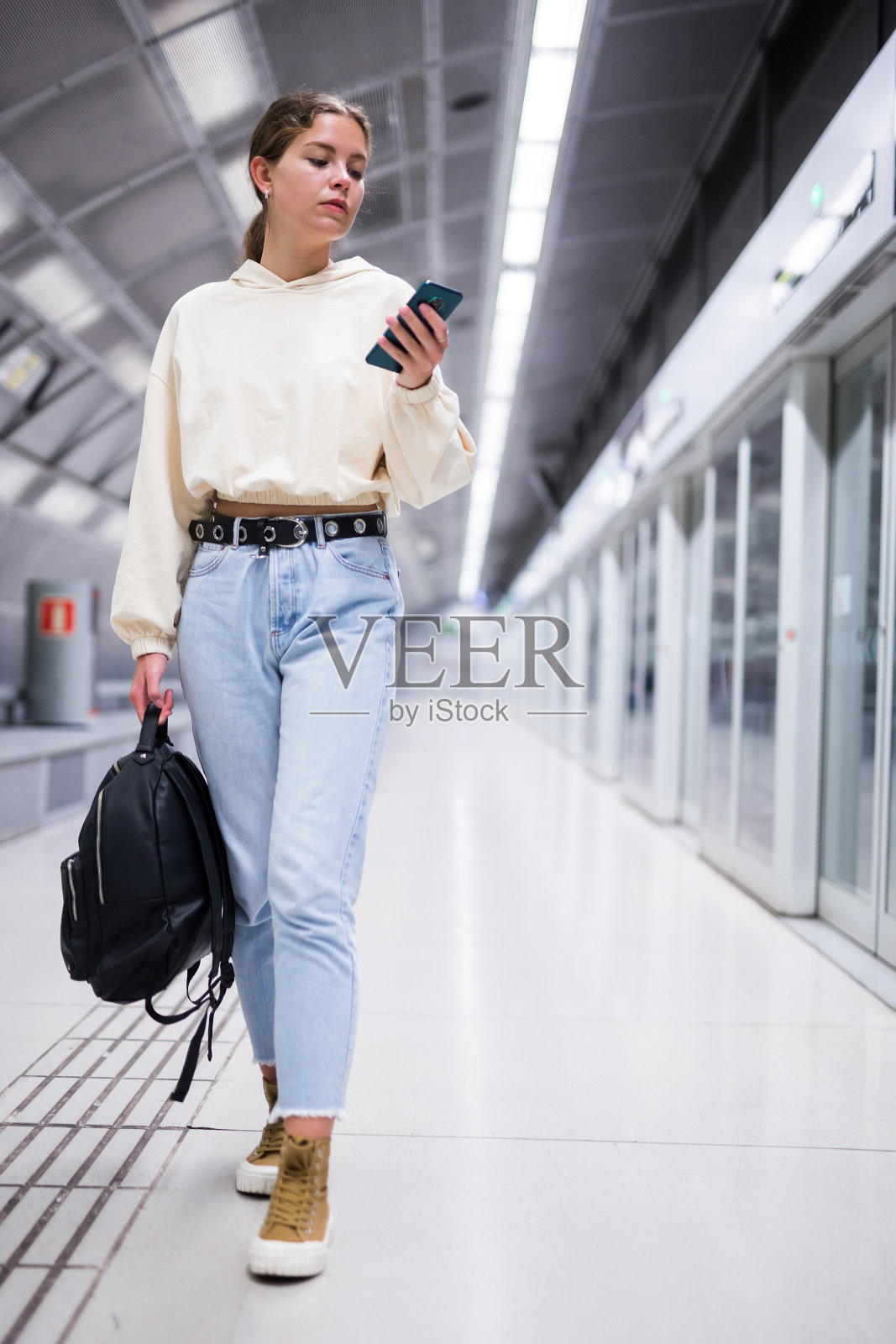 年轻的欧洲女性拿着手机在等地铁照片摄影图片