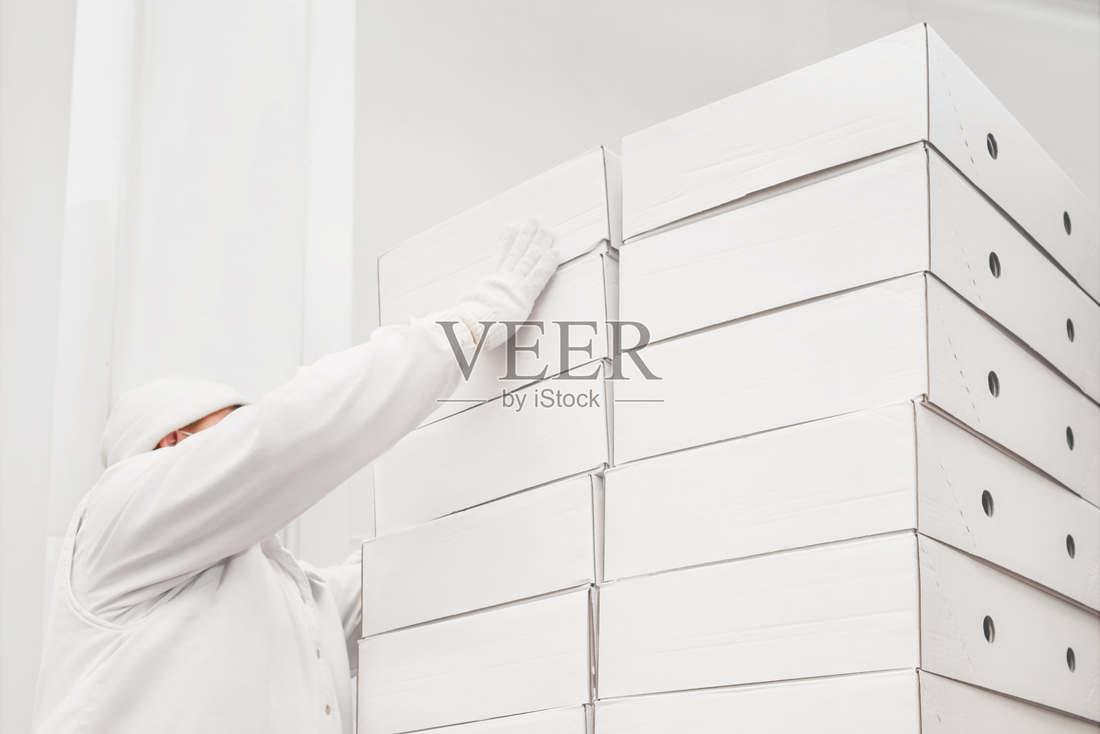 一个人把一个纸箱放在一堆上。检查库存。装运箱。仓库存储。仓库工人分拣装运箱。销售物流中心。仓库工人放纸箱。照片摄影图片