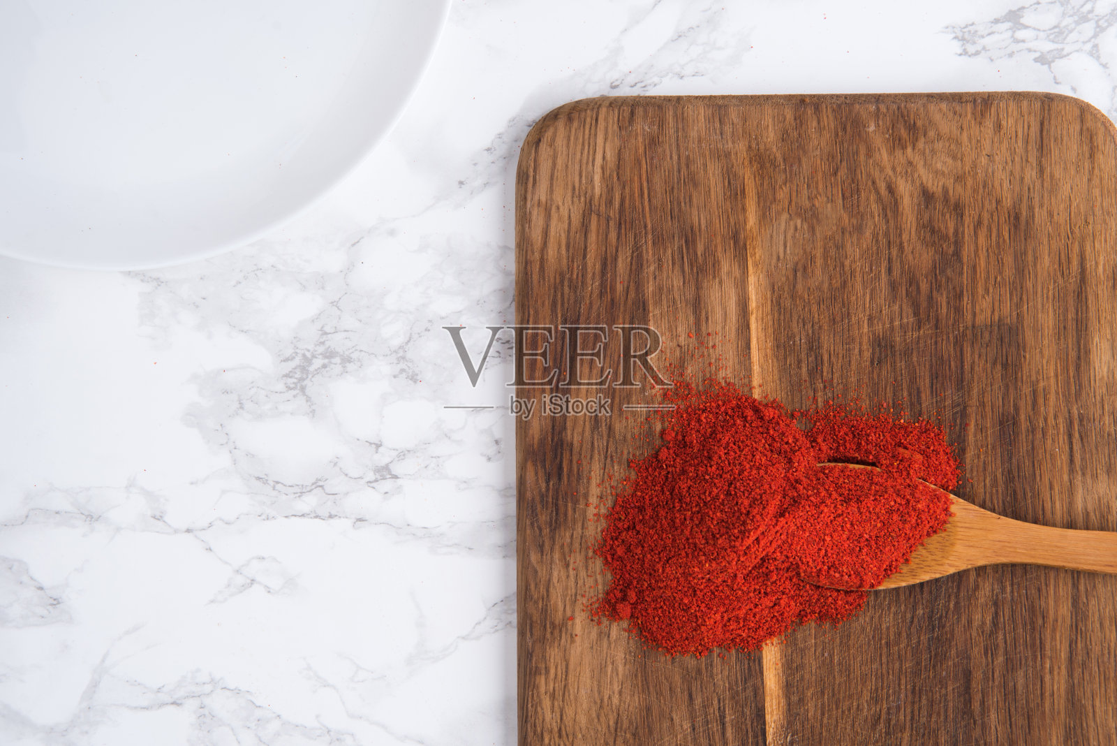 用木勺蘸上辣椒粉放在砧板上照片摄影图片