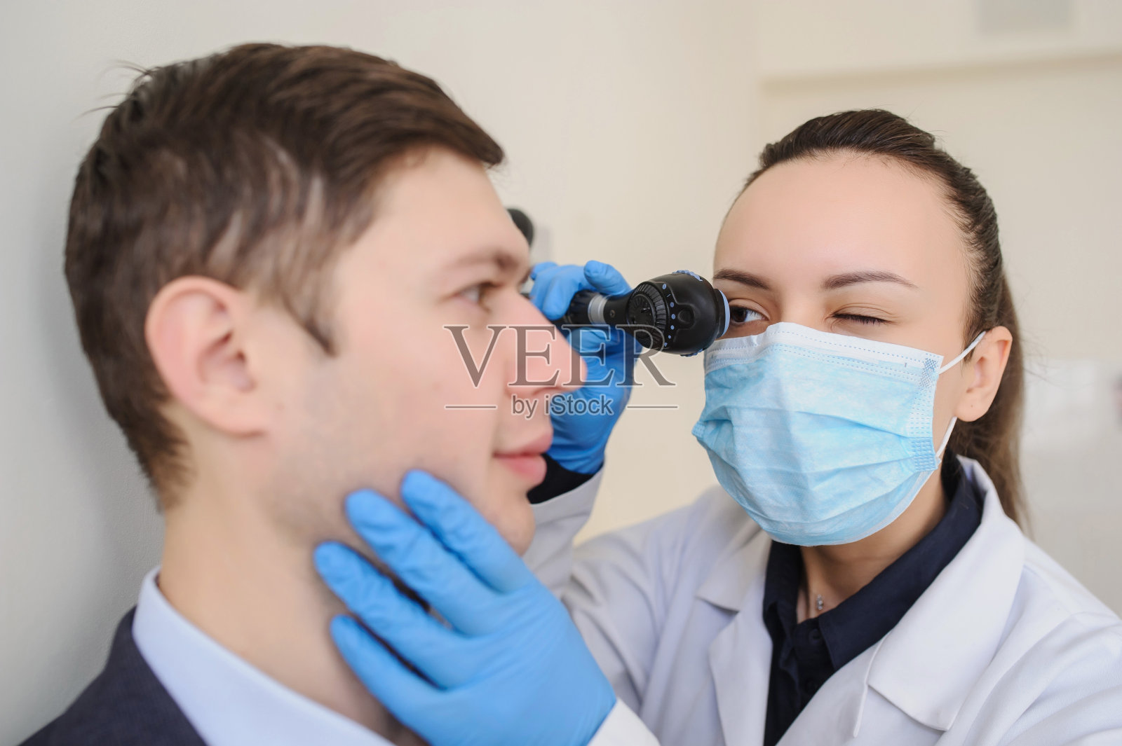 验光师用检眼镜检查男人的眼睛照片摄影图片